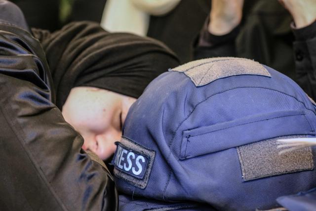 A woman mourns next to a press ballistic helmet as relatives and friends gather at the house of Amal Khalil, a veteran correspondent for the daily newspaper Al-Akhbar who was killed in a reported Israeli airstrike in southern Lebanon, in the village of Bisariyeh on April 23, 2026. An Israeli airstrike killed the Lebanese journalist and wounded another on April 22, while they were working near the border with Israel, according to their employer and rescuers. (Photo by MAHMOUD ZAYYAT / AFP)