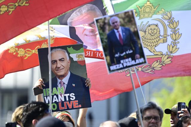 Demonstrators display signs depicting son of Iran's last shah, exiled Crown Prince Reza Pahlavi after he held a press conference at the BPK (Bundespressekonferenz) building in Berlin, on April 23, 2026. (Photo by John MACDOUGALL / AFP)