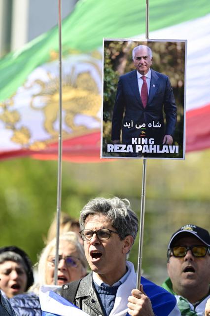 A demonstrator holds a signs depicting the son of Iran's last shah, exiled Crown Prince Reza Pahlavi after a press conference at the BPK (Bundespressekonferenz) building in Berlin, on April 23, 2026. (Photo by John MACDOUGALL / AFP)