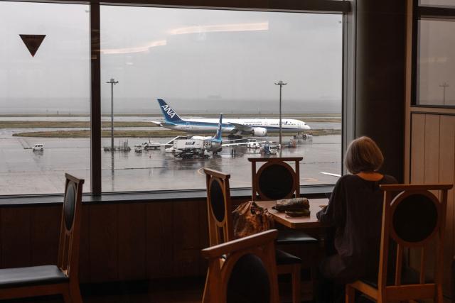 An All Nippon Airways (ANA) Boeing 787-10 passenger aircraft is seen past the window of a restaurant at Tokyo's Haneda Airport on April 23, 2026. (Photo by Philip FONG / AFP)