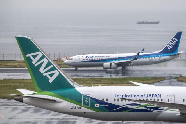 An All Nippon Airways (ANA) Boeing 737-800 (top) deploys reverse thrust during landing as seen from the observation area of Tokyo's Haneda Airport on April 23, 2026. (Photo by Philip FONG / AFP)