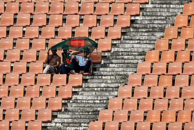 Bangladeshi fans holding a national flag cheer from near-empty stands during the third one-day international (ODI) cricket match between Bangladesh and New Zealand at the Bir Sreshtho Flight Lieutenant Matiur Rahman Stadium in Chittagong on April 23, 2026. (Photo by Munir UZ ZAMAN / AFP)