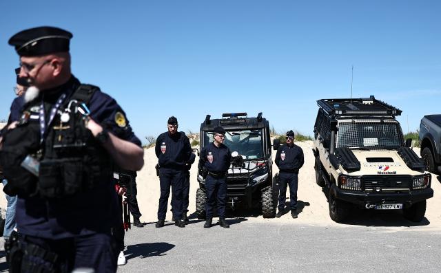 French Republican Security Corps (CRS - Compagnies Republicaines de Securite) police officers stand as they wait for France's Interior Minister and British Home Secretary's visit for a presentation of the operational resources used to counter illegal immigration, on the shores of Zuydcoote, near Dunkirk, on April 23, 2026. Britain and France have agreed a new three-year deal to stop undocumented migrants making the risky journey across the Channel in small boats, the two sides announced. Under the deal, France pledged to increase law enforcement on the coast by more than half to fight irregular migration to Britain -- reaching 1,400 officers by 2029. The Sandhurst treaty sets out the UK's financial contribution to French efforts to stop migrants attempting the perilous sea crossing to Britain. (Photo by Sameer AL-DOUMY / AFP)