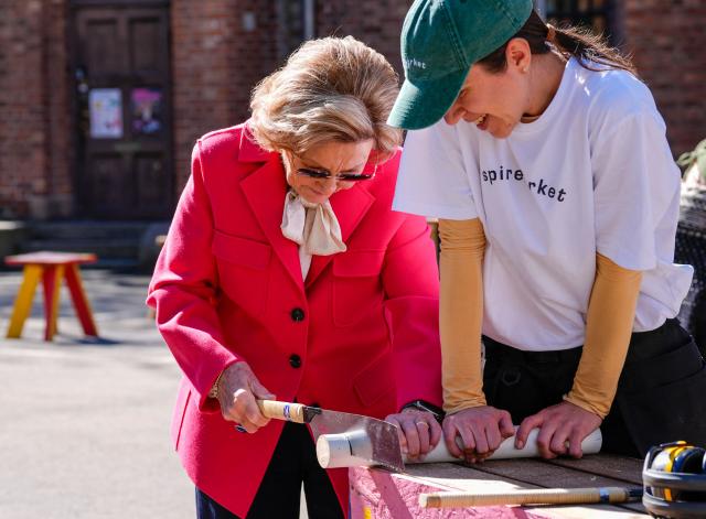 Queen Sonja of Norway (L) uses a tool to cut wood during a meeting with young design talents organised by non-profit organization Spireverket at Sofienberg Church in Oslo on April 23, 2026. The Queen was given a tour of the site, to see how Spireverket contributes to the work of transforming Sofienberg Church into a cultural center for children, youth and the neighborhood. (Photo by Lise Åserud / NTB / AFP) / Norway OUT