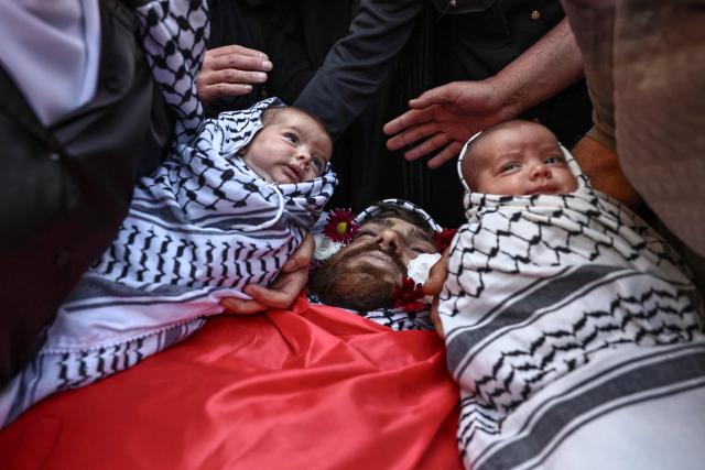 EDITORS NOTE: Graphic content / Relatives hold two infants next to the body of Awda Atef Awawdeh during his funeral in Deir Dibwan in the Israeli-occupied West Bank, on April 23, 2026. The Palestinian health ministry said Israeli settlers shot dead a Palestinian man in the occupied West Bank on April 22, the third victim of deadly gunfire in two days. The ministry said 25-year-old Awawdeh was killed by settler gunfire in the central West Bank town of Deir Dibwan, just east of Ramallah. (Photo by Zain JAAFAR / AFP)