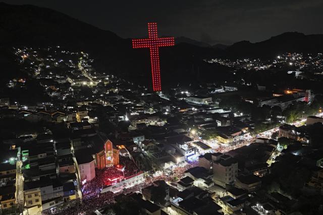 The figure of a Catholic cross is recreated with drones next to the Sao Jorge church during the Saint George's Day celebrations at the Quintino neighborhood in Rio de Janeiro, Brazil on April 23, 2026. (Photo by Pablo PORCIUNCULA / AFP)