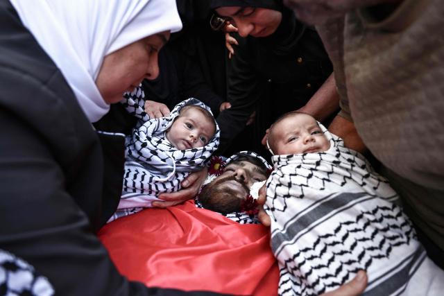 EDITORS NOTE: Graphic content / Relatives hold the twin infant daughters of Awda Atef Awawdeh next to his body during his funeral in Deir Dibwan in the Israeli-occupied West Bank, on April 23, 2026. The Palestinian health ministry said Israeli settlers shot dead a Palestinian man in the occupied West Bank on April 22, the third victim of deadly gunfire in two days. The ministry said 25-year-old Awawdeh was killed by settler gunfire in the central West Bank town of Deir Dibwan, just east of Ramallah. (Photo by Zain JAAFAR / AFP)