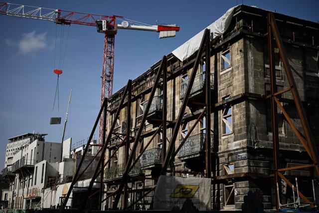 Steel supports hold a preserved 19th-century facade in place as construction advances at the Canopia urban redevelopment site near the Saint-Jean railway station in Bordeaux, south-western France,2026. The city's redevelopment push comes as the European Central Bank warned that the Iran conflict risks pushing energy-dependent European economies into stagflation, with French construction firms reporting fuel and materials cost hikes across active sites. (Photo by Philippe LOPEZ / AFP)