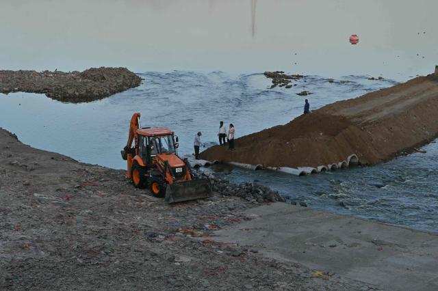 Workers redevelop a floodgate at Sabarmati river in Vasna, Ahmedabad on April 23, 2026. (Photo by Shammi MEHRA / AFP)