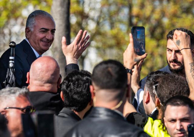 The son of Iran's last shah, exiled Crown Prince Reza Pahlavi (L) smiles at wellwishers as he walks off the stage after addressing a demonstration in Berlin, on April 23, 2026. Pahlavi said during a press conference that any negotiation with the religious authorities in Tehran amounted to a "policy of appeasement," expressing hope that new protests would eventually overthrow the regime. (Photo by John MACDOUGALL / AFP)