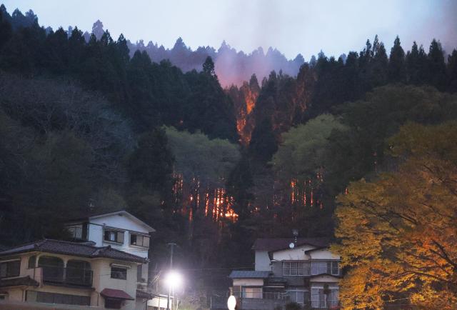 Flames encroach on homes during a forest fire in Otsuchi Town, Iwate Prefecture on April 23, 2026. (Photo by JIJI PRESS / AFP) / Japan OUT