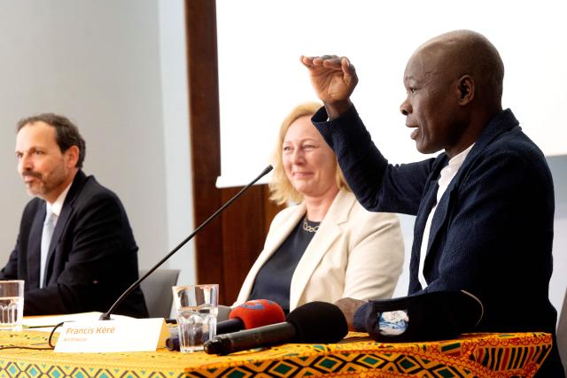 Architect Francis Kere (R), who designed the Goethe-Institut building, speaks during a press conference at the Goethe-Institut German cultural centre in Dakar on April 16, 2026. The bricks are local, the open-air ventilation is abundant, and a single towering baobab unites it all: architect Francis Kere's new building in Dakar is simultaneously sustainable and distinctly African.
A dual national of Burkina Faso and Germany, Kere is the only African to have won the Pritzker Prize (2022), architecture's most prestigious award. (Photo by SEYLLOU / AFP)