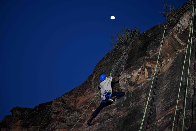 This photograph taken on March 28, 2026 shows a climber scaling a rock wall during a rock climbing festival at a sandstone cliffs site in Karnataka's Badami town. India, a country obsessed with cricket, has seen a surge in popularity in climbing but those who want to compete internationally have had to crowd-fund and there is little government recognition or help.
The Indian Mountaineering Foundation (IMF) estimates there are tens of thousands of people who sport-climb regularly, with more than a dozen climbing gyms opening in the last decade.
But the rise in those picking it up as a professional career is slow -- high costs and scarce sponsorship deals hold back many. (Photo by Sajjad HUSSAIN / AFP) / TO GO WITH India-climbing, FOCUS by Pitcha Dangprasith, with Aishwarya Kumar in Bengaluru