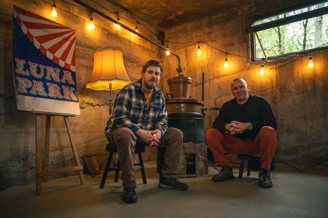 Ivan Lakatos (L) and Miroslav Basic (R) pose in their gin distillery in the village of Belegis, near Stara Pazova, on March 28, 2026. In Serbia, as across much of the gin industry, juniper is not farmed but instead gathered from wild bushes by hand. Juniper has declined in parts of Europe over the past few decades particularly in lowland areas where it once grew. Studies show the species is struggling to regenerate in many areas, with climate change, grazing and habitat loss all contributing to declining populations. (Photo by Andrej ISAKOVIC / AFP)