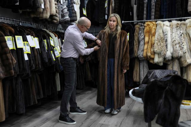 Larry Cowit (L), owner of Madison Avenue Furs shop, assists a customer in his store in New York City, on March 10, 2026. New York is thawing out after a particularly cruel winter that's included debates over fur's revival as influencers push the look and retail sites report a jump in searches for vintage pieces. Business owners like Cowit, who inherited and runs his family's Madison Avenue Furs, are celebrating a sales spike. (Photo by ANGELA WEISS / AFP)