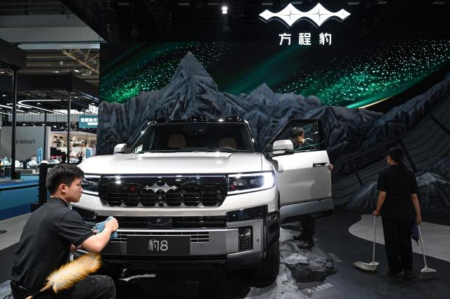 Staff members prepare next to BYD Fangchengbao's Leopard 8 at the Beijing Auto Show in Beijing on April 24, 2026. (Photo by JADE GAO / AFP)