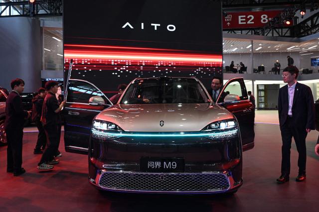 People try Huawei's AITO M9 model car is displayed at the Beijing Auto Show in Beijing on April 24, 2026. (Photo by JADE GAO / AFP)
