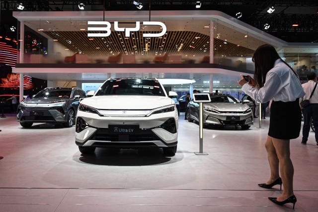 A woman takes a photo of BYD's Song Ultra eletric car at the Beijing Auto Show in Beijing on April 24, 2026. (Photo by JADE GAO / AFP)