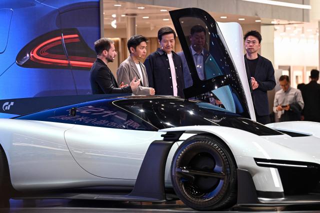 Lei Jun (3rd-L), Chairman and CEO of Chinese electronics company Xiaomi, stands next to Xiaomi's Vision Gran Turismo concept car at the Beijing Auto Show in Beijing on April 24, 2026. (Photo by JADE GAO / AFP)
