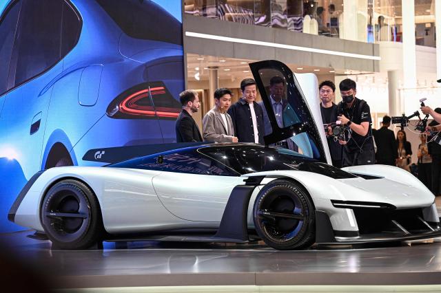 Lei Jun (3rd-L), Chairman and CEO of Chinese electronics company Xiaomi, stands next to Xiaomi's Vision Gran Turismo concept car at the Beijing Auto Show in Beijing on April 24, 2026. (Photo by JADE GAO / AFP)