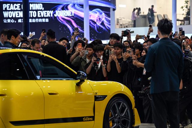 People take photos of the CEO of Chinese electronics company Xiaomi's Lei Jun (L) next to the Xiaomi's electric car SU7 Ultra at the Beijing Auto Show in Beijing on April 24, 2026. (Photo by JADE GAO / AFP)