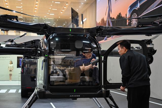 Staff members clean an electric flying car “Land Aircraft Carrier” by Xpeng's subsidiary Aridgat at the Beijing Auto Show in Beijing on April 24, 2026. (Photo by JADE GAO / AFP)