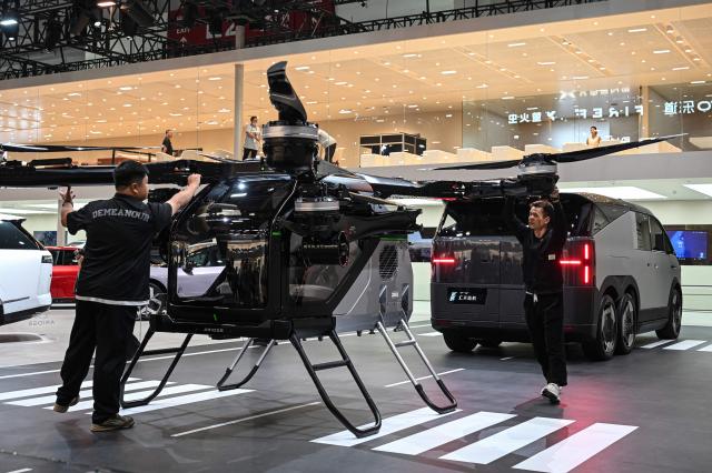 Staff members check an electric flying car “Land Aircraft Carrier” by Xpeng's subsidiary Aridgat at the Beijing Auto Show in Beijing on April 24, 2026. (Photo by JADE GAO / AFP)