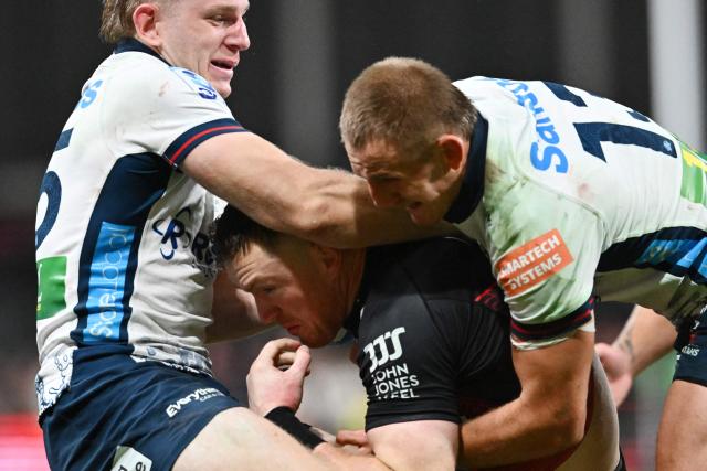 Crusaders' Dallas McLeod (C) is tackled by Waratahs' Max Jorgensen (L) and Joey Walton during the Super Rugby Pacific match between the Canterbury Crusaders and NSW Waratahs at One New Zealand Stadium in Christchurch on April 24, 2026. (Photo by Sanka VIDANAGAMA / AFP)