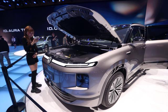 A woman stands next to a Volkswagen ID ERA 9X on the opening day of the Beijing Auto Show in Beijing on April 24, 2026. (Photo by CN-STR / AFP) / China OUT