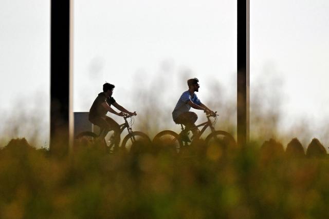Men cycle along a beach in Kuwait City on April 24, 2026. (Photo by YASSER AL-ZAYYAT / AFP)