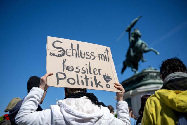 A demonstrator holds his placard reading:"An End to Fossil Fuel Policies" as he and students, teachers and environmental organizations attend a demonstration called by the Fridays For Future movement, "Our budget, our Future"  for an end of subsidies for oil and gas on April 24,2026, outside of the Hoffburg palace at the Helden square in Vienna, Austria. (Photo by Joe Klamar / AFP)