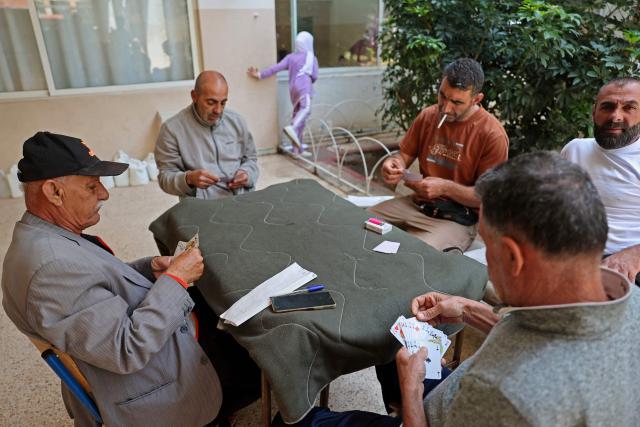 Men play cards at a school in the coastal southern city of Sidon on April 24, 2026, as displaced residents prepare to return after an extention of the ceasefire. Israel and Lebanon extended their shaky ceasefire by three weeks, President Donald Trump said, as the United States remained at a standstill in negotiations with Iran to end the Middle East war. (Photo by Anwar AMRO / AFP)