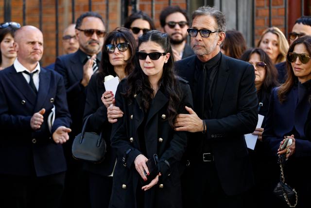 Nadia Fares' daughter Cylia Chasman (C) and her father US Producer Steven Chasman (C-R) react after the funeral ceremony of French actress Nadia Fares at the Saint-Jean de Montmartre church in Paris on April 24, 2026. Nadia Fares died on April 17, 2026, aged 57, after being found unconscious in a swimming pool in Paris and several days in a coma. (Photo by SIMON WOHLFAHRT / AFP)