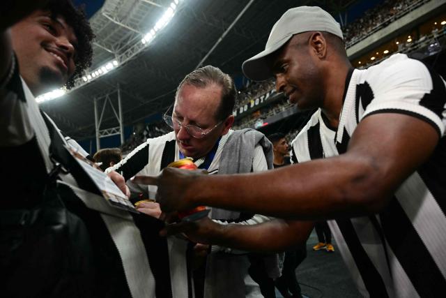 (FILES) Botafogo owner and CEO John Textor (C) signs autographs for fans after his team's championship win during the Brasileirao Seria A football match between Botafogo and Sao Paulo at the Nilton Santos Olympic stadium in Rio de Janeiro, Brazil, on December 8, 2024. The Rio de Janeiro football club announced on April 24, 2026, that U.S. business magnate John Textor had been removed from Botafogo’s management by a Brazilian arbitration court. (Photo by Mauro PIMENTEL / AFP)