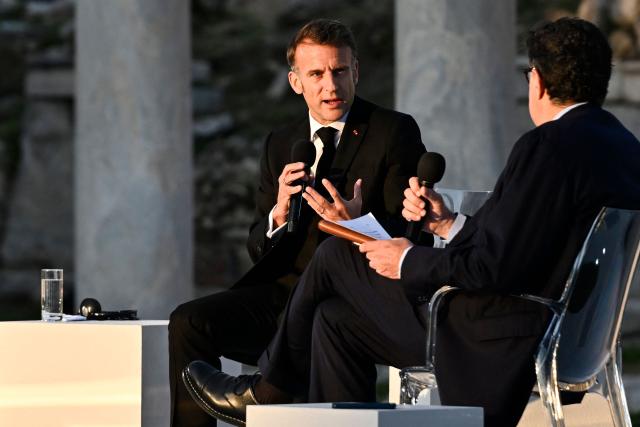France's President Emmanuel Macron (L) speaks with Kathimerini Executive Editor Alexis Papachelas (R) on stage during an event at the Roman Agora in Athens, on April 24, 2026. Emmanuel Macron visits Athens to strengthen Franco-Greek cooperation on defence and security. (Photo by Aris MESSINIS / AFP)