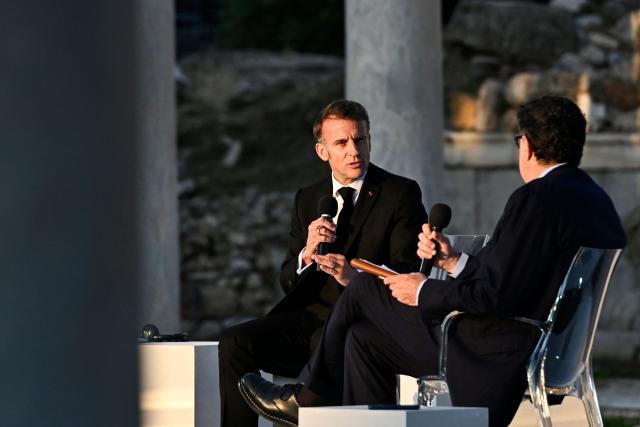 France's President Emmanuel Macron (L) speaks with Kathimerini Executive Editor Alexis Papachelas (R) on stage during an event at the Roman Agora in Athens, on April 24, 2026. Emmanuel Macron visits Athens to strengthen Franco-Greek cooperation on defence and security. (Photo by Aris MESSINIS / AFP)