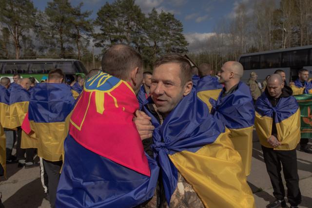 Released Ukrainian prisoners of war (POWs) wrapped with Ukrainian national flags hug each other following a prisoner exchange at an undisclosed location, in the Chernihiv region on April 24, 2026, amid the Russian invasion of Ukraine. Russia and Ukraine swapped 193 captured soldiers each, the second exchange this month in one of the few areas of cooperation between Moscow and Kyiv. The two countries have exchanged thousands of POWs throughout the four-year war -- with the swaps often the only result of otherwise stalled talks on ending the conflict. (Photo by Roman PILIPEY / AFP)