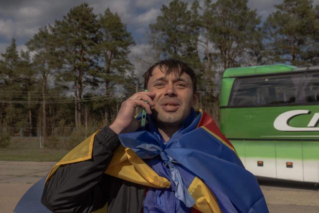 A released Ukrainian prisoner of war (POW), wrapped in a Ukrainian national flag, makes a phone call with a relative following a prisoner exchange at an undisclosed location, in the Chernihiv region on April 24, 2026, amid the Russian invasion of Ukraine. Russia and Ukrain swapped 193 captured soldiers each, the second exchange this month in one of the few areas of cooperation between Moscow and Kyiv. The two countries have exchanged thousands of POWs throughout the four-year war -- with the swaps often the only result of otherwise stalled talks on ending the conflict. (Photo by Roman PILIPEY / AFP)