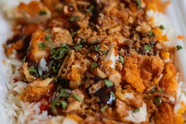 This photograph shows a take away "Crousty" dish in an appartment in Saint-Mandé, east of Paris, on April 24, 2026. An affordable, high-calorie dish made with rice and fried chicken and popularized on social media, the "crousty" has become a commercial phenomenon and a flagship fast-food item that eclipses burgers, tacos, and kebabs. (Photo by Martin LELIEVRE / AFP)