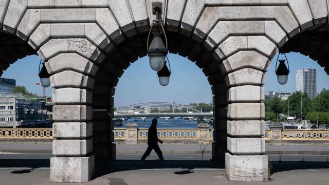 A pedestrian walks crossing the Bercy bridge from the southern bank (rive gauche) to the northern bank (rive droite) under a aerial metro railway with a view of the Seine river, in eastern Paris, on April 24, 2026. (Photo by Martin LELIEVRE / AFP)