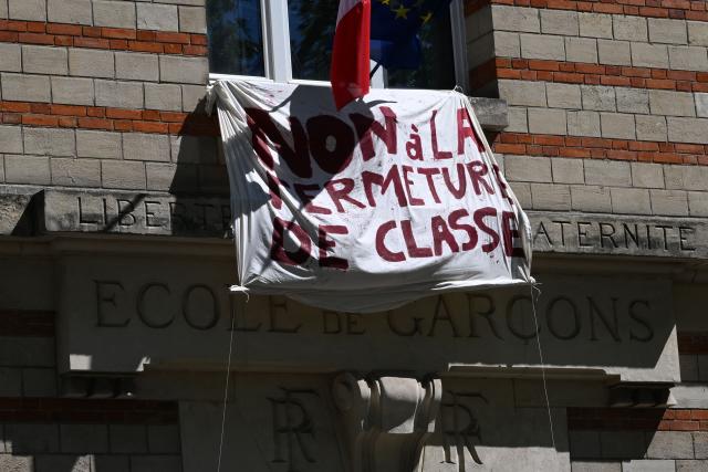 This photograph shows a view of the facade of a public elementary school Charenton with a banner reading "No to the closing of classrooms", east of Paris on April 24, 2026. (Photo by Martin LELIEVRE / AFP)