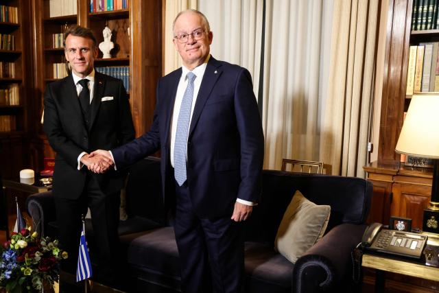 Greece's President Konstantinos Tasoulas (R) shakes hands as he welcomes France's President Emmanuel Macron (L) upon arrival ahead of a meeting at the Presidential Palace in Athens, on April 24, 2026. Emmanuel Macron is in a two-days visit to Greece to strengthen Franco-Greek cooperation on defence and security. (Photo by Ludovic MARIN / AFP)
