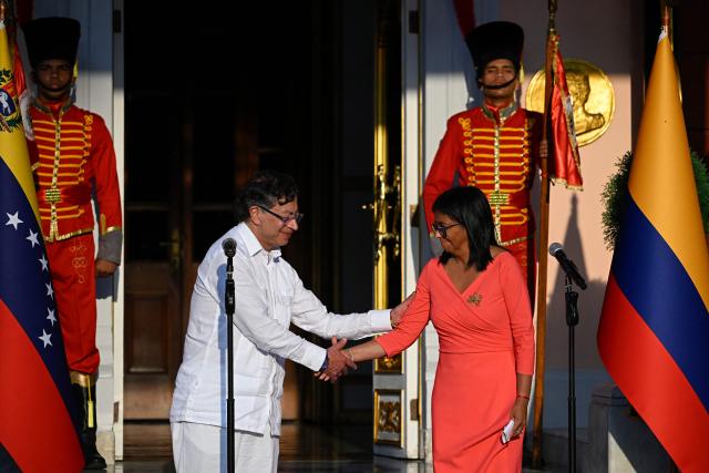 Venezuela's interim President Delcy Rodriguez (R) and Colombian President Gustavo Petro shake hands after delivering statements following a bilateral meeting at the Miraflores presidential palace in Caracas on April 24, 2026. Colombia's President Gustavo Petro arrived in Venezuela on April 24 for a bilateral meeting with interim President Delcy Rodriguez, focusing on border security and energy cooperation. (Photo by Federico PARRA / AFP)