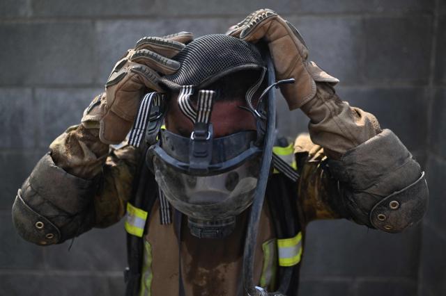 A Salvadoran soldier puts on a self-contained breathing apparatus (SCBA) during a post-earthquake rescue simulation in the final phase of a 36 hour emergency exercise, held as part of the CENTAM Guardian 2026 military drills, at the Engineers Corps (CIFA) facilities in San Juan Opico, El Salvador, on April 24, 2026. (Photo by Marvin RECINOS / AFP)