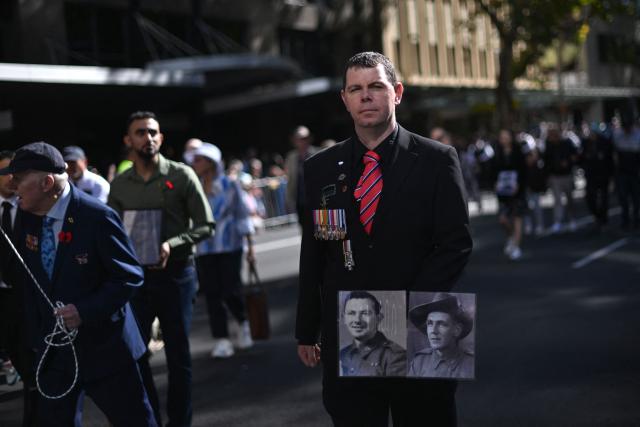 A man carries photos of soldiers during the annual ANZAC (Australian and New Zealand Army Corps) Day parade in Sydney on April 25, 2026. Dawn services were held across the two countries on the anniversary of the ill-fated 1915 campaign of the Australian and New Zealand Army Corps that left 11,500 of them dead in what is now Turkey during World War I. (Photo by Saeed KHAN / AFP)