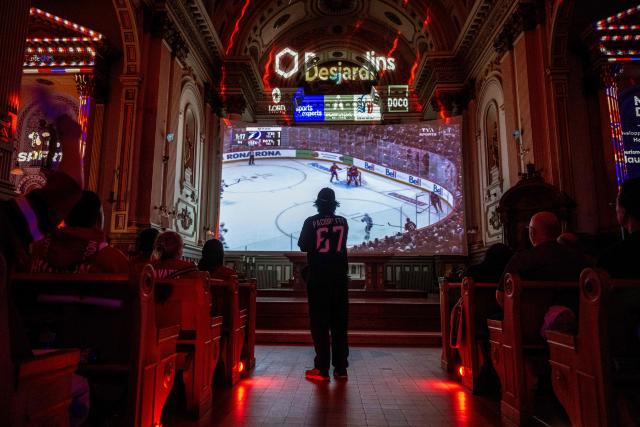 Montreal Canadiens fans watch the live broadcast of the Stanley Cup playoff game against Tampa Bay Lightning inside the Cathedrale Saint-Jean-l’Evangeliste, in Saint-Jean-sur-Richelieu, Quebec, on April 24, 2026. The cathedral, about 25 miles (40 kms) southeast of Montreal, is being transformed into a hockey "high mass" during the National Hockey League (NHL) playoffs. (Photo by ANDREJ IVANOV / AFP)