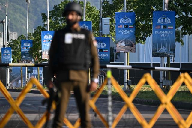 A police officer stands guard beside posters highlighting Pakistan's mediation of Iran–US peace talks near the Serena Hotel at the Red Zone area in Islamabad on April 25, 2026. Iran's foreign minister arrived in Islamabad on April 24 and US envoys headed to the Pakistani capital in a bid to kickstart a new round of peace negotiations amid a fragile ceasefire. (Photo by Aamir QURESHI / AFP)