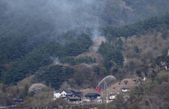 A fire engine sprays water on a hill side near homes in the town of Otsuchi, in Iwate Prefecture on April 25, 2026. (Photo by ANDREW CABALLERO-REYNOLDS / AFP)