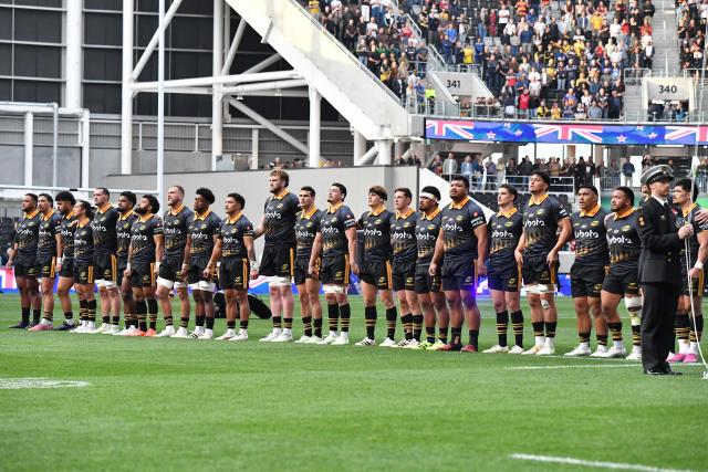 Hurricanes players line up for an ANZAC (Australian and New Zealand Army Corps) Day commemorations prior to the round 11 Super Rugby Pacific match between the Hurricanes and Brumbies at One New Zealand Stadium in Christchurch on April 25, 2026. (Photo by Sanka Vidanagama / AFP)