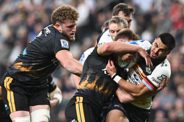 Brumbies' Lachlan Shaw (R) is tackled by Hurricanes' defence during round 11 Super Rugby Pacific match between the Hurricanes and Brumbies at One New Zealand Stadium in Christchurch on April 25, 2026. (Photo by Sanka VIDANAGAMA / AFP)